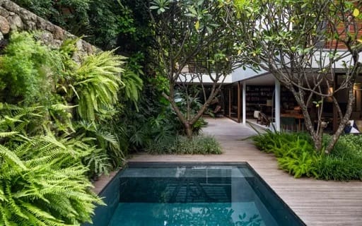 Piscina cercada por jardim tropical