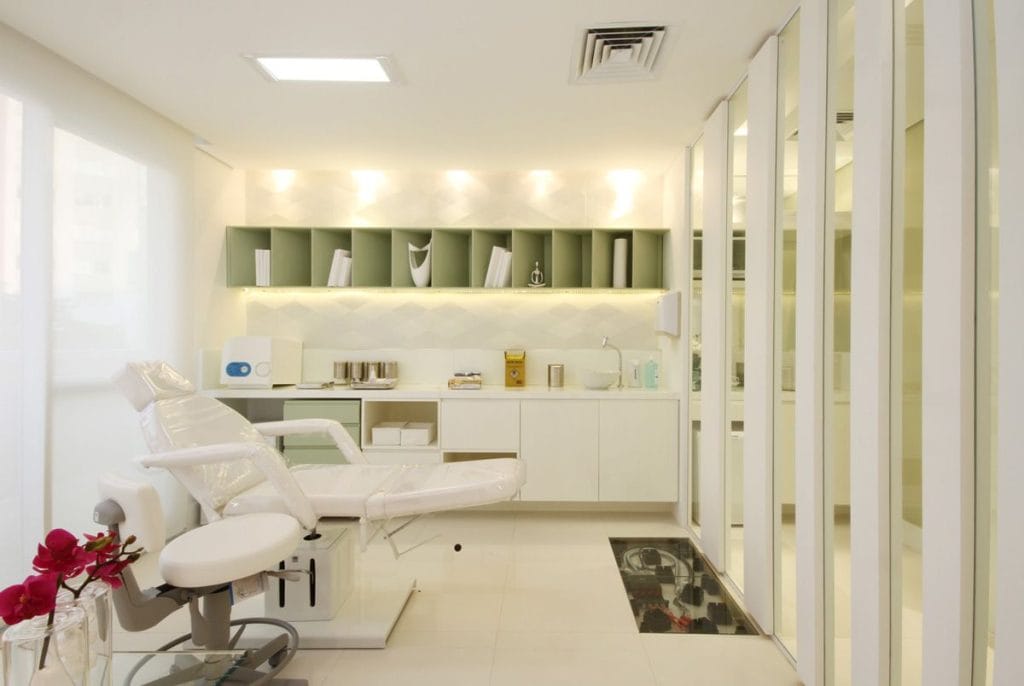 Clínica decorada em branco com parede espelhada e nicho verde